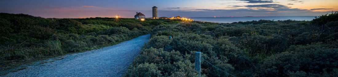 caminho-cercado-por-arbustos-e-vegetacao-que-leva-um-povoado-e-um-mar-ao-por-sol