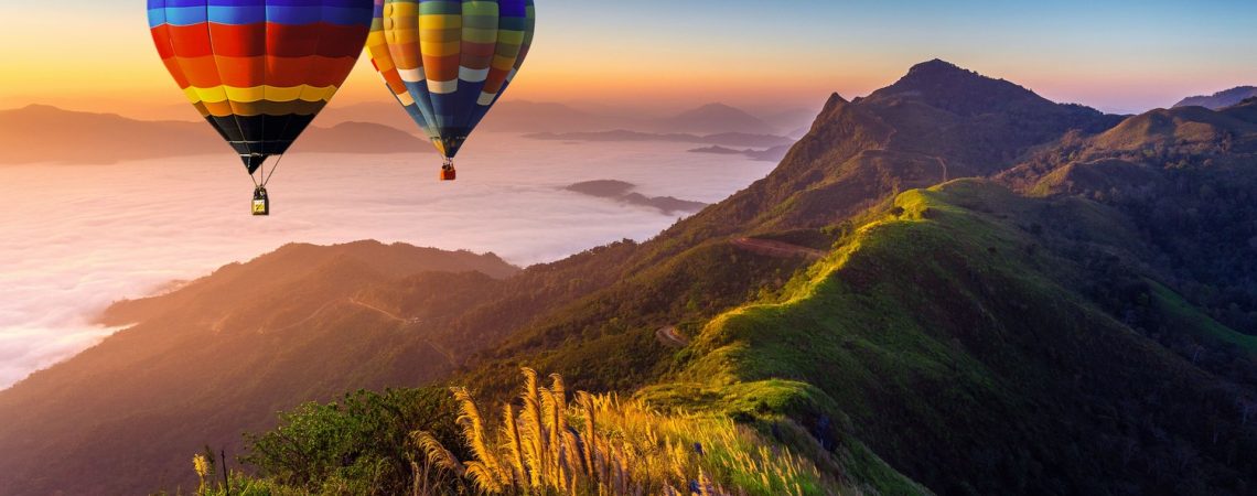 paisagem-de-nevoeiro-matinal-e-montanhas-com-baloes-de-ar-quente-ao-nascer-sol